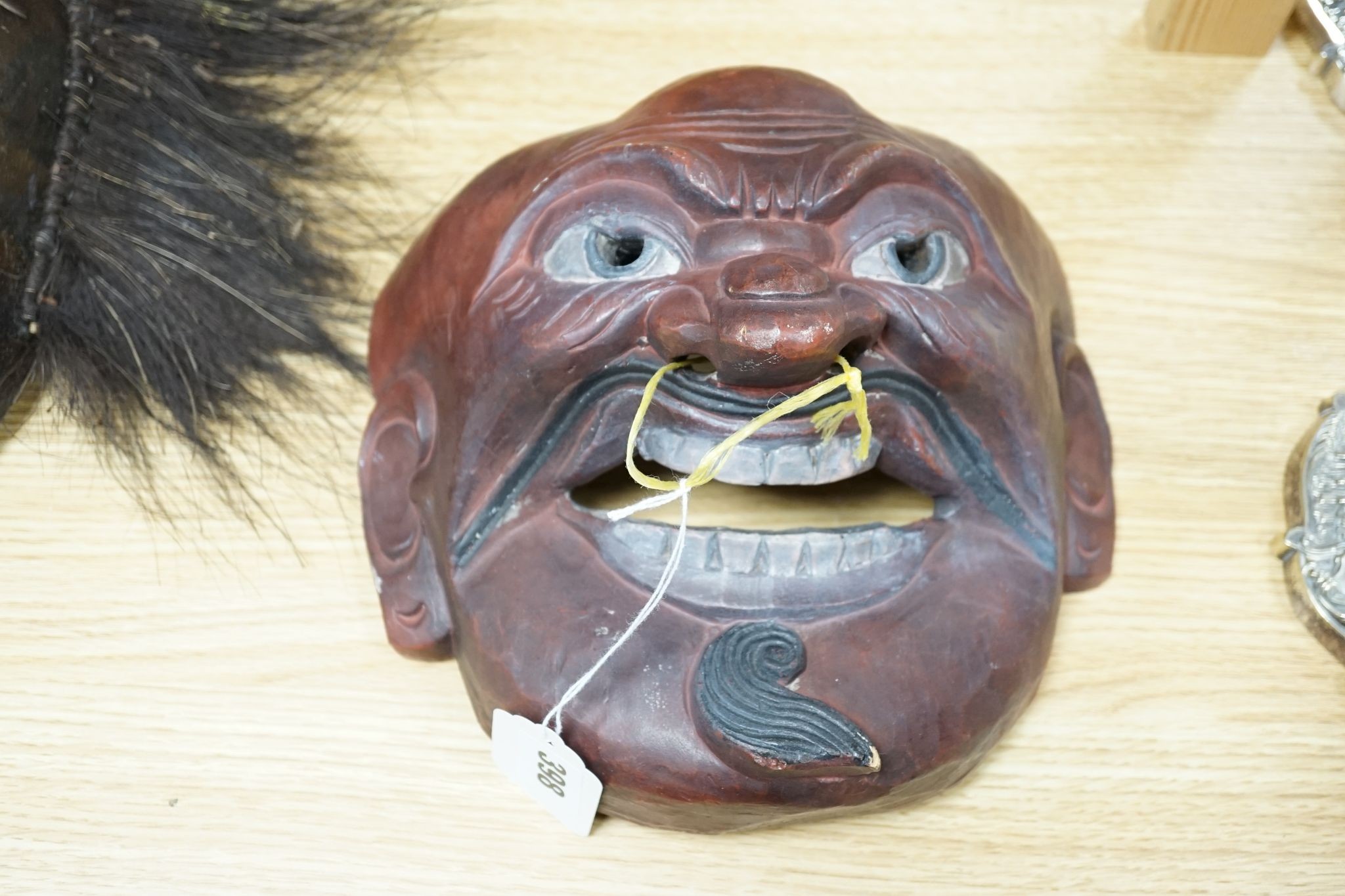 Two Japanese carved wood masks, an African beaded mask and three similar rattles